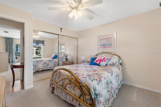 carpeted bedroom with a textured ceiling, ceiling fan, visible vents, baseboards, and a closet