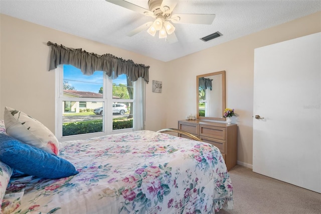 carpeted bedroom with a ceiling fan, visible vents, and a textured ceiling