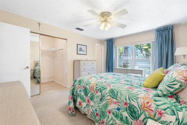 carpeted bedroom with a ceiling fan, a textured ceiling, visible vents, and a closet