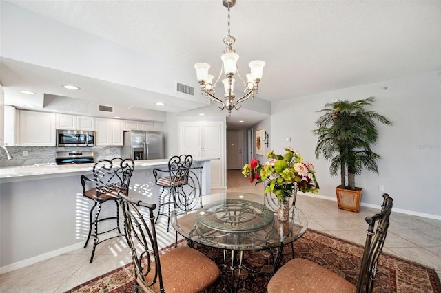 dining room with light tile patterned floors, baseboards, visible vents, and a notable chandelier