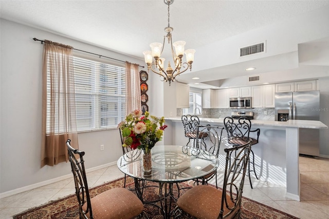 dining area featuring light tile patterned floors, a notable chandelier, visible vents, and baseboards