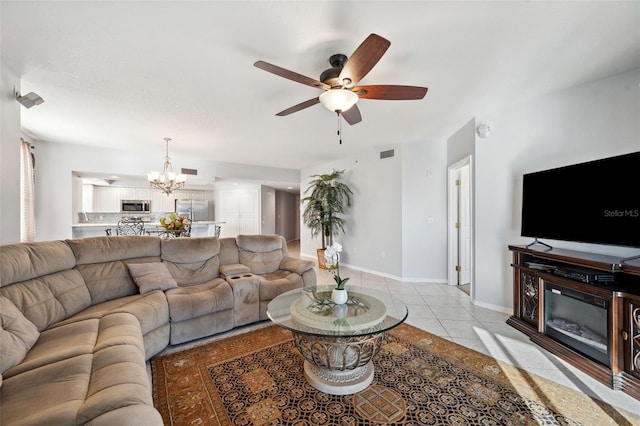 living area featuring ceiling fan with notable chandelier, visible vents, baseboards, and light tile patterned floors