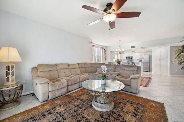 living area with light tile patterned floors, ceiling fan with notable chandelier, and baseboards