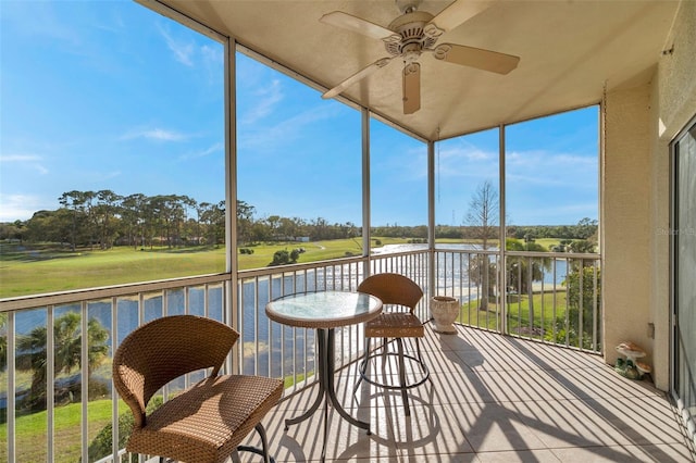 sunroom with a ceiling fan and a water view