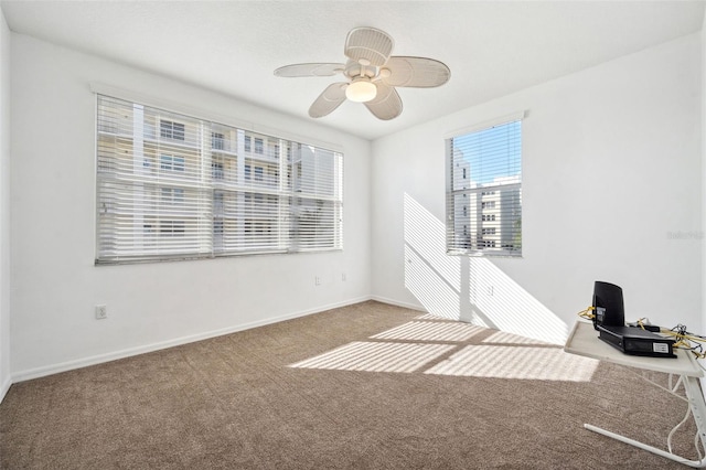 carpeted spare room with a ceiling fan and baseboards