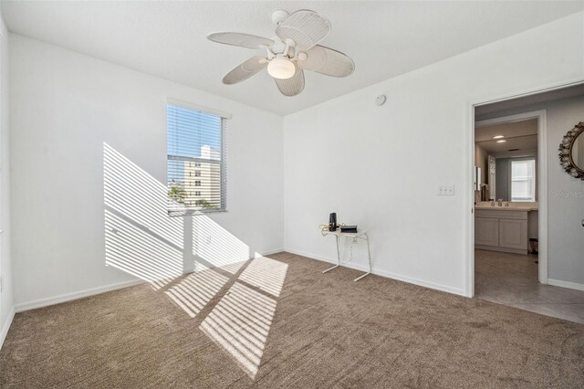 empty room with carpet, a sink, a wealth of natural light, and baseboards