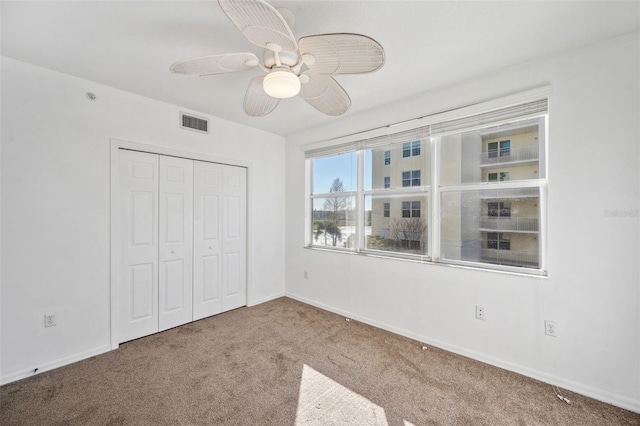 unfurnished bedroom with carpet floors, baseboards, visible vents, and a closet