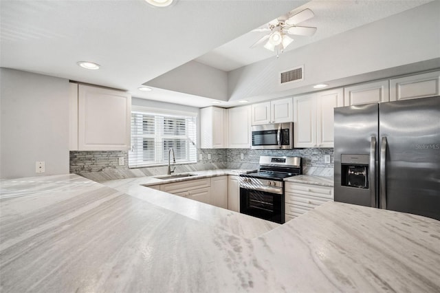 kitchen featuring appliances with stainless steel finishes, visible vents, a sink, and decorative backsplash