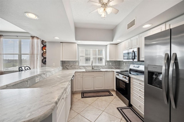 kitchen with light tile patterned floors, tasteful backsplash, visible vents, appliances with stainless steel finishes, and a sink