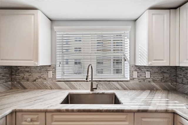 kitchen featuring tasteful backsplash, white cabinetry, and a sink