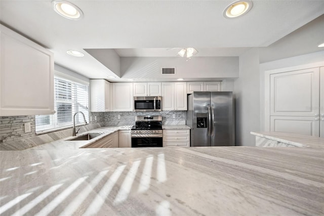 kitchen featuring recessed lighting, stainless steel appliances, a sink, visible vents, and decorative backsplash