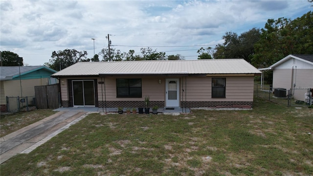 view of front of house with a front yard, metal roof, cooling unit, and fence