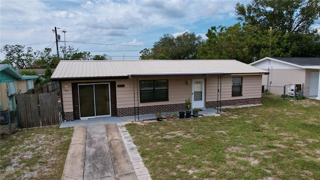 view of front of home featuring metal roof, a front lawn, fence, and brick siding