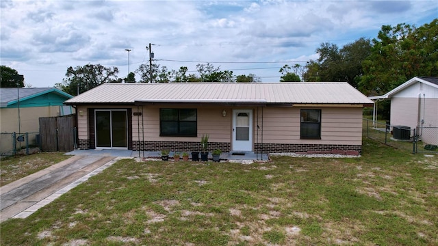 single story home with a gate, central AC, metal roof, fence, and a front lawn