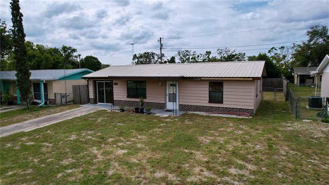 ranch-style home featuring central AC unit, metal roof, a gate, fence, and a front yard