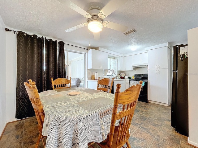 dining room with a ceiling fan, visible vents, and a textured ceiling