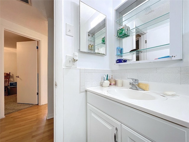 bathroom featuring vanity, decorative backsplash, and wood finished floors