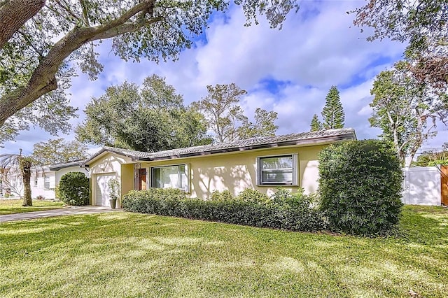 ranch-style house with driveway, an attached garage, stucco siding, a front lawn, and a tiled roof