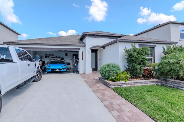 view of front of house featuring an attached garage, a front yard, concrete driveway, and stucco siding