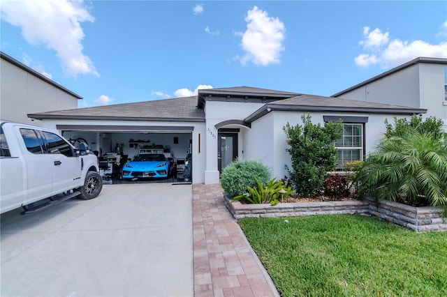 view of front of property with driveway, a front yard, an attached garage, and stucco siding