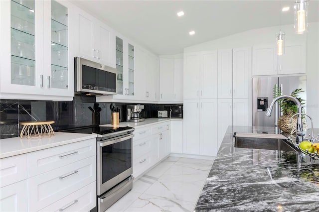 kitchen featuring tasteful backsplash, white cabinets, appliances with stainless steel finishes, marble finish floor, and a sink