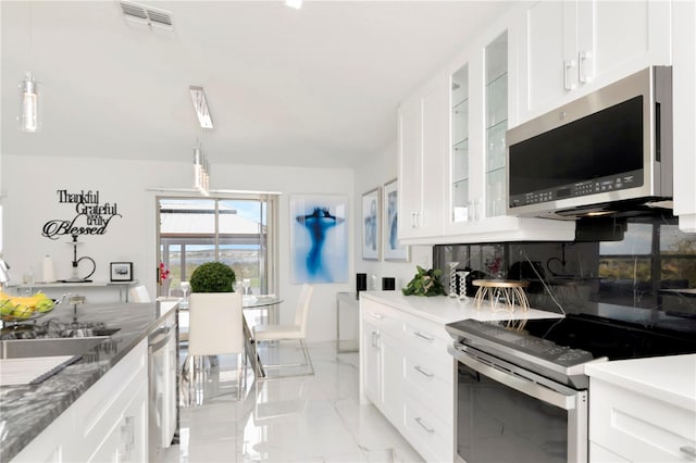 kitchen featuring white cabinets, decorative backsplash, glass insert cabinets, marble finish floor, and stainless steel appliances