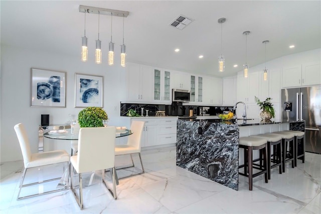 kitchen featuring visible vents, a kitchen breakfast bar, marble finish floor, appliances with stainless steel finishes, and decorative backsplash