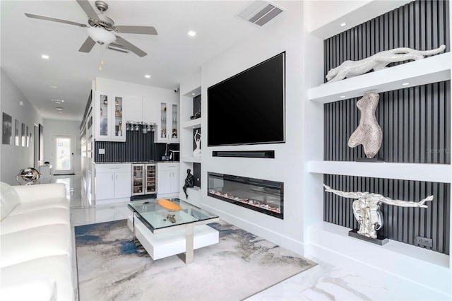 living area featuring marble finish floor, wine cooler, a glass covered fireplace, and visible vents