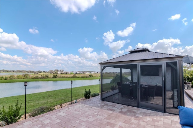 view of patio with a sunroom and a water view