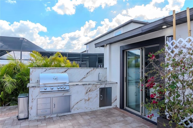 view of patio with an outdoor kitchen, grilling area, and glass enclosure