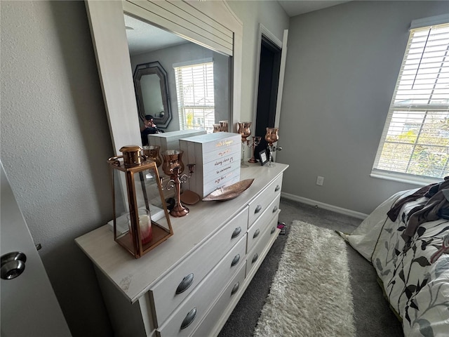 bedroom featuring multiple windows, dark carpet, and baseboards