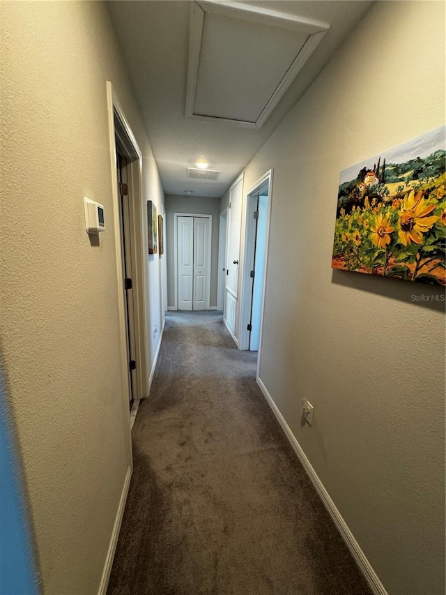 corridor with dark colored carpet and baseboards