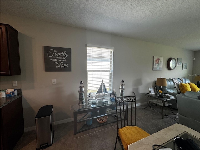 interior space featuring a textured ceiling, dark tile patterned floors, and baseboards