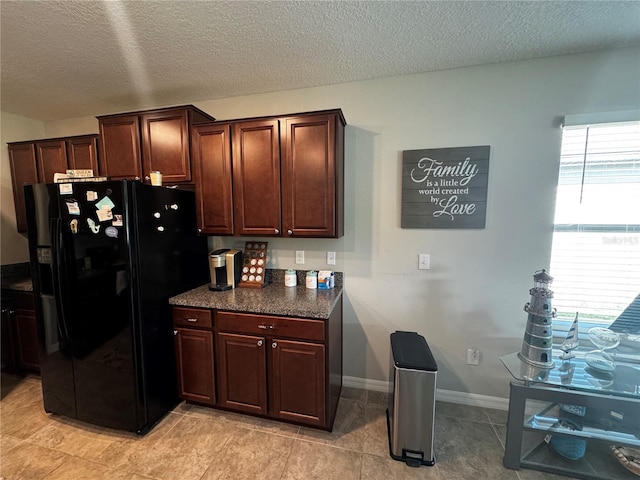 kitchen featuring baseboards, black fridge with ice dispenser, dark countertops, dark brown cabinets, and a textured ceiling