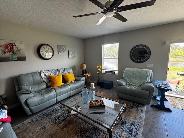 tiled living area with plenty of natural light, baseboards, ceiling fan, and a textured ceiling