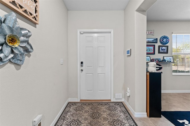 doorway with tile patterned floors and baseboards