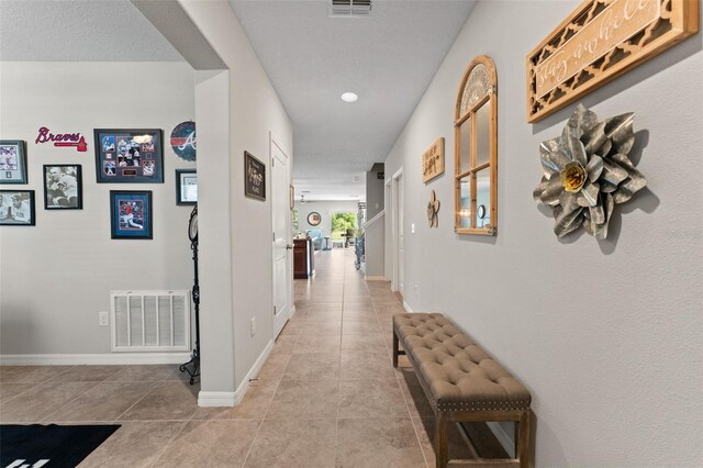 hallway featuring visible vents, tile patterned floors, and baseboards