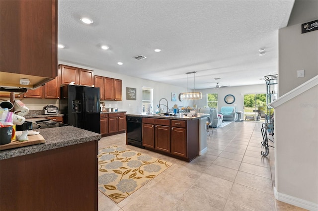 kitchen with a sink, a textured ceiling, black appliances, open floor plan, and visible vents