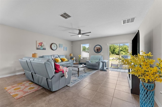 tiled living area with baseboards, a ceiling fan, and visible vents