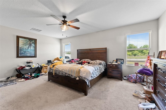 bedroom with a textured ceiling, carpet, visible vents, and ceiling fan