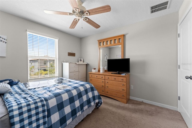 carpeted bedroom featuring baseboards, visible vents, a textured ceiling, and ceiling fan