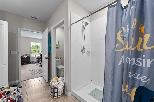 full bath featuring a tile shower, toilet, tile patterned floors, and visible vents