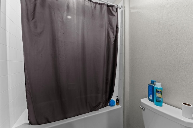 full bathroom with a textured wall, shower / bath combo with shower curtain, and toilet