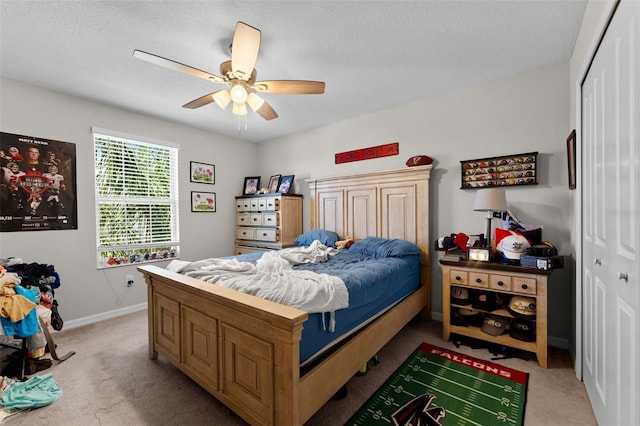 bedroom with light carpet, a textured ceiling, baseboards, a closet, and ceiling fan