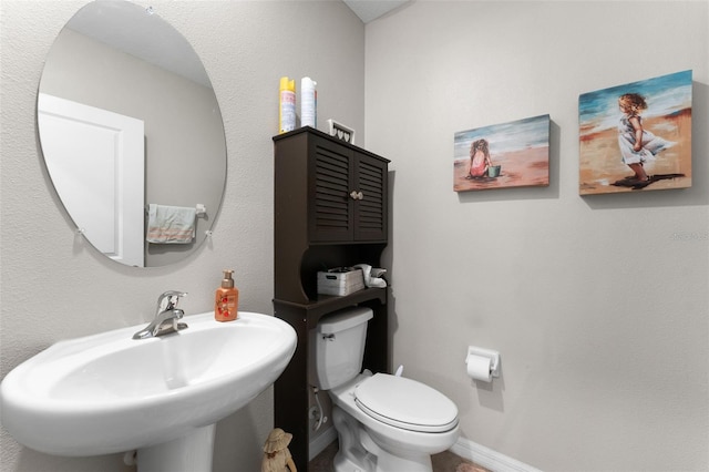 bathroom featuring baseboards, a sink, and toilet