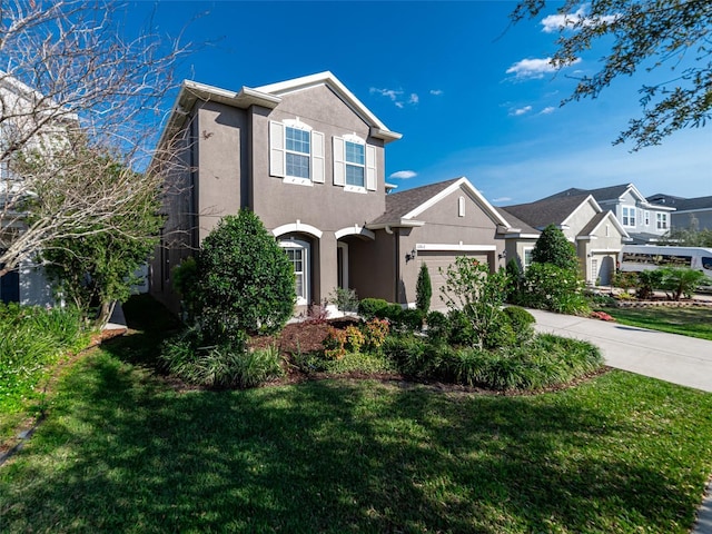 traditional home with a garage, driveway, a front yard, and stucco siding