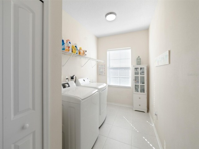 laundry room with laundry area, light tile patterned floors, baseboards, and washer and dryer