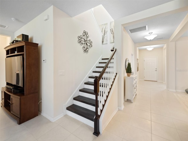 stairs with tile patterned flooring, visible vents, and baseboards