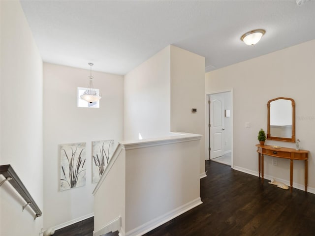 hall with baseboards, an upstairs landing, and wood finished floors