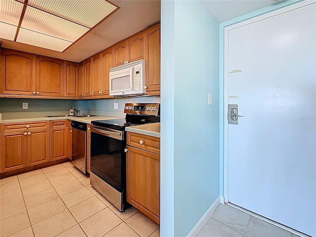 kitchen featuring brown cabinets, stainless steel appliances, light countertops, and baseboards